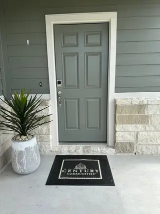 A welcoming entrance with a green door, potted plant, and Century Communities mat in Northpark South by Century Communities (Porter, TX).