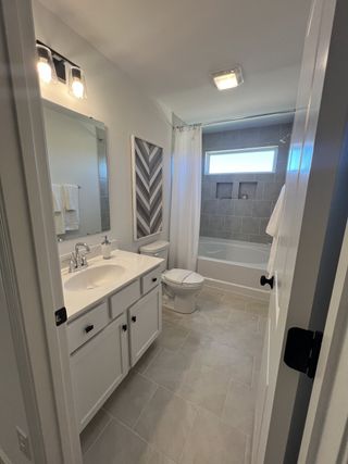 A sleek bathroom with modern lighting, chevron wall art, and a clean design featuring a tub and spacious vanity.
