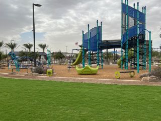A vibrant playground surrounded by lush greenery in Allen Ranches: Fiesta Collection by Taylor Morrison (Litchfield Park, AZ).