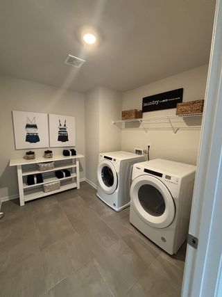 A modern laundry room featuring sleek appliances, chic decor, and practical shelving for organized storage.