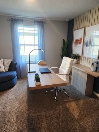 A stylish home office with a wood-accented wall, natural light, and cozy furnishings in Copes Landing by D.R. Horton (Jacksonville, FL).