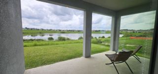 Street view A serene patio overlooking a tranquil lake and manicured lawn, perfect for relaxation and enjoying nature.