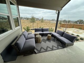 A covered patio with modern outdoor seating and a backyard fire pit in Veramendi by Brightland Homes (New Braunfels, TX).