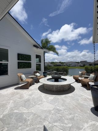 A serene patio with elegant seating, a modern fire pit, and lush landscaping overlooking a tranquil lake.