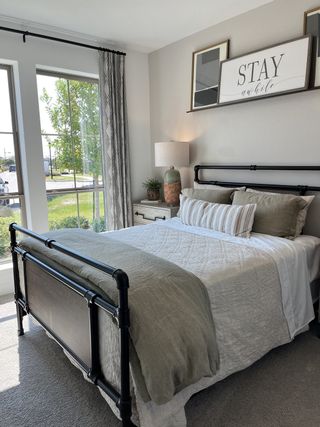 A cozy bedroom with a vintage metal bedframe, soft linens, large windows, and calming decor.