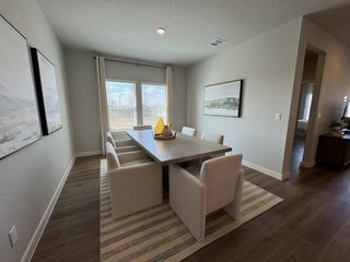A modern dining room with a sleek wooden table, plush chairs, and large windows, accented by serene landscape artwork.