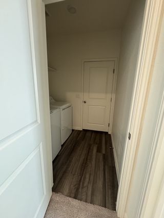 A sleek laundry room with wood flooring, white appliances, and ample storage space.