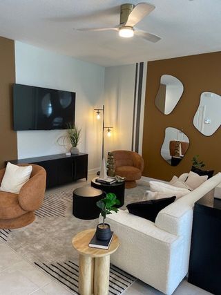 Model Home A chic living room with modern furniture, abstract mirrors, accent walls, and stylish lighting for a cozy ambiance.