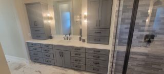 A chic bathroom featuring a sleek gray vanity, modern fixtures, and textured wall tiles.