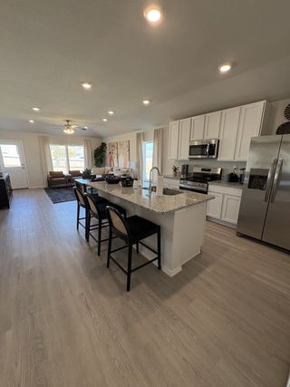 A contemporary kitchen with white cabinetry, granite countertops, and an island with barstool seating in Hunters Ranch by Rausch Coleman Homes (San Antonio, TX).