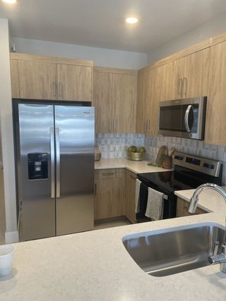 A modern kitchen with wood cabinetry, stainless steel appliances, and a quartz countertop.