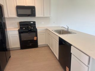A modern kitchen with sleek black appliances, white cabinets, and a spacious countertop.