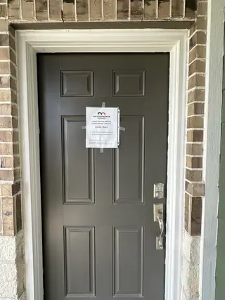 Street view A sleek gray door with brick surround and modern keypad in Seven Oaks Townhomes by HistoryMaker Homes (Tomball, TX).