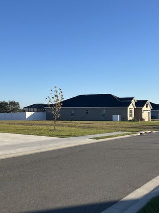 A modern home with a spacious lawn and a sleek design in Otter Woods Estates by Highland Homes of Florida (Auburndale, FL).