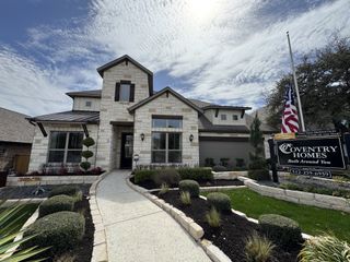 Street view A stunning stone exterior home with professional landscaping and charming curb appeal in Palmera Bluff by Coventry Homes (Leander, TX).