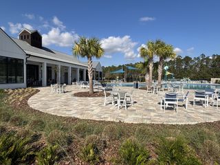 A vibrant community pool area with seating and palm trees in Harmony West by D.R. Horton (St. Cloud, FL).