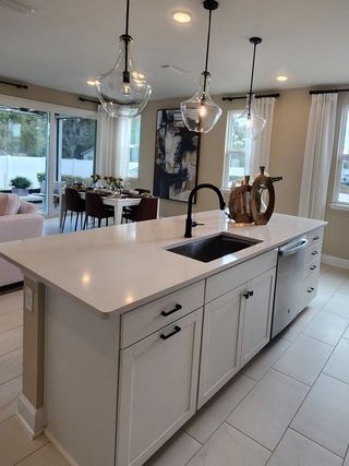 A modern kitchen with an island, pendant lights, and dining area. Bright, open concept with elegant decor.