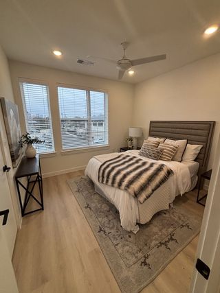Model Home Cozy bedroom with a plush bed, elegant rug, soft lighting, and city views through large windows.