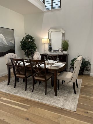 A sophisticated dining room with elegant chairs, a dark wooden table, and chic decor on a plush area rug.
