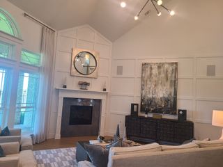 A sophisticated living room featuring high ceilings, stylish lighting, and a modern fireplace with tasteful decor.