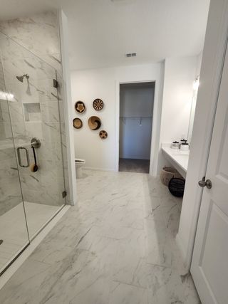 A sleek bathroom with marble flooring, a glass shower, and modern decor accents for a luxurious touch.