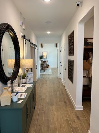 A welcoming hallway with wood floors, elegant decor, and a warm palette leading to an inviting dining area.