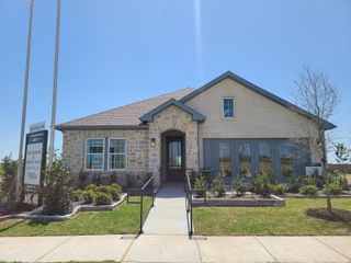 A charming stone-brick home with lush landscaping at Brookshire at Legacy Hills-60s by Ashton Woods, Celina, TX.