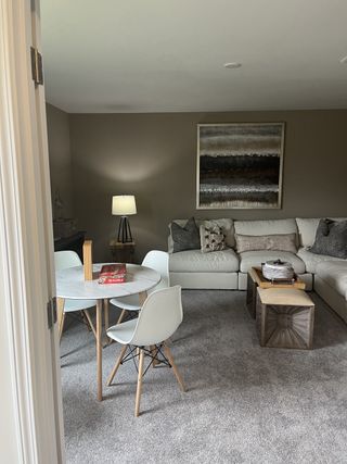 Model Home A cozy living room with a sectional sofa, round dining table, and modern artwork on warm-toned walls.