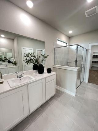 A modern bathroom with sleek white cabinetry, a glass shower, and elegant tile flooring.