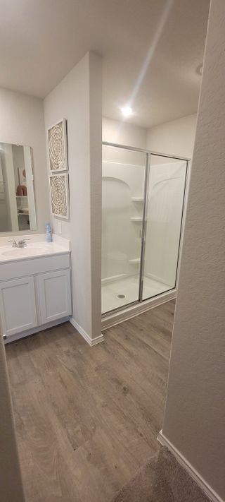 A modern bathroom featuring a sleek glass shower, white vanity, and elegant wall art.