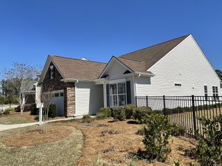 A charming single-story home with white siding and stone accents, in Four Seasons at Lakes of Cane Bay by K. Hovnanian® Homes in Summerville, SC.