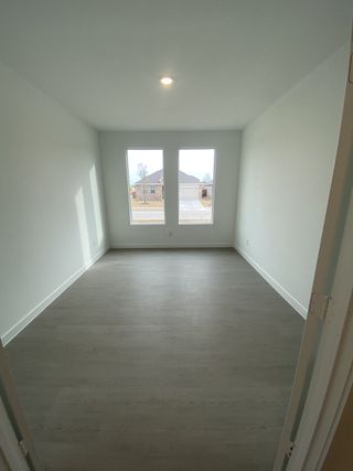 A bright room with large windows, wood flooring, and a recessed ceiling light, offering ample natural light.