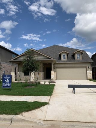 Street view A charming stone and siding home with manicured lawn in Saddleback at Santa Rita Ranch by Pulte Homes (Liberty Hill, TX).