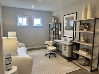 A cozy home office features stylish shelving, modern desk, plush seating, and soft lighting. Perfect for work and relaxation.