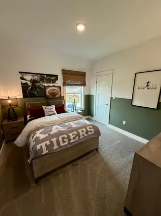 A cozy bedroom with sports-themed decor, featuring a football poster and stylish bedding, perfect for relaxation.