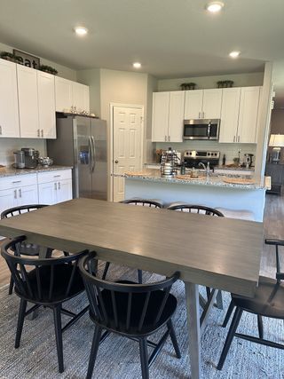Modern kitchen with white cabinets, granite countertops, stainless steel appliances, and a sleek dining table.