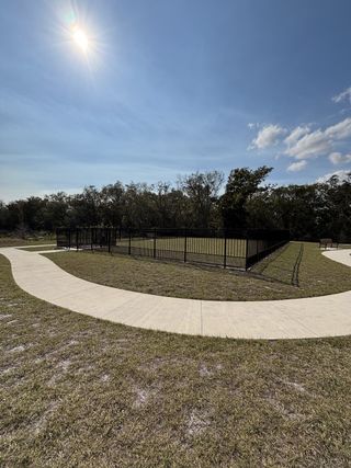 A spacious dog park with a walking path, open green space, and fenced-in play areas in Gardenia Reserve by Mattamy Homes (Apopka, FL).