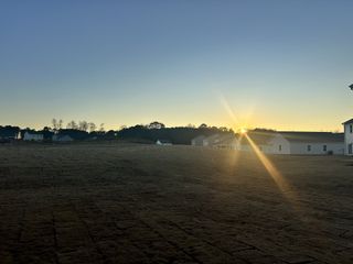 A serene sunset over new homes in Green Hill by Starlight Homes, set in the tranquil landscape of Louisburg, NC.