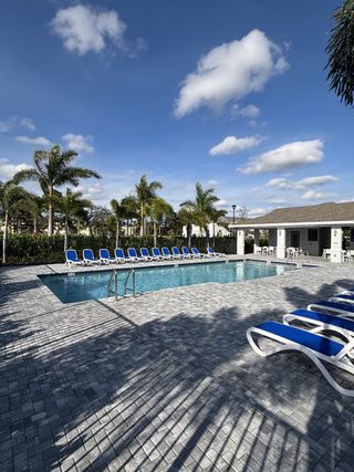 A serene community pool with blue lounge chairs and palm trees in Veranda Landing by Lennar (Port St. Lucie, FL).