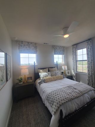 Model Home A cozy bedroom featuring elegant patterned curtains, a plush bed with decorative pillows, and soft lighting for a restful ambiance.