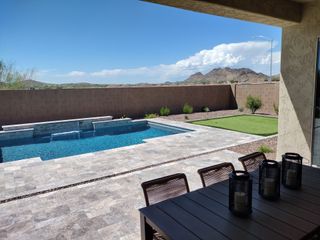 A serene backyard with a sparkling pool, paved patio, and mountain views, perfect for relaxation.
