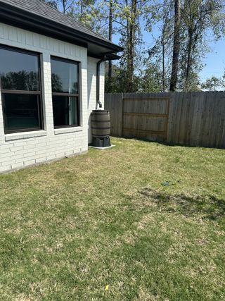 A modern home with a rain barrel and fenced yard in ARTAVIA 55' Lots by J. Patrick Homes (Conroe, TX).