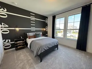 A sports-themed bedroom featuring a striking black accent wall with yard line graphics, cozy bed, and natural light.