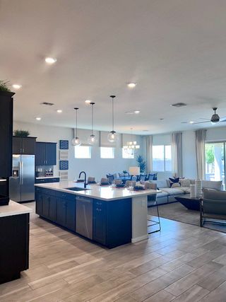 Model Home An open-concept kitchen and living room with sleek cabinetry, pendant lighting, and ample natural light.