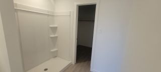 Model Home A modern shower area with built-in shelves and a spacious closet entrance, featuring sleek finishes and neutral tones.