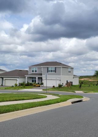 A modern gray two-story home with a tidy yard in Ridgeview by Trinity Family Builders (Clermont, FL).