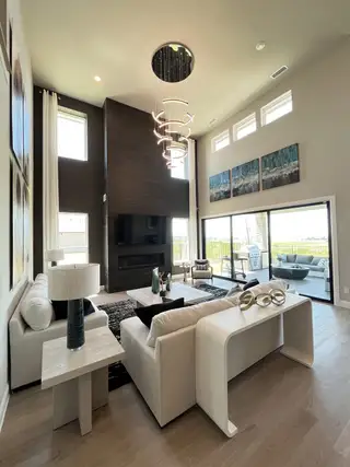 A modern living room with high ceilings, sleek fireplace, abstract art, and elegant lighting.