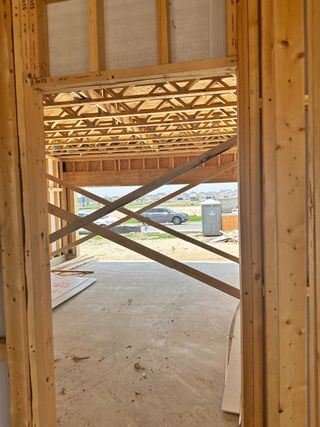 A view of a home under construction with exposed wooden beams and framing.