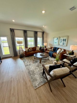 Model Home A cozy living room featuring leather sofas, a modern rug, large windows with drapes, and stylish decor accents.