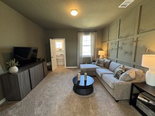Cozy living room with a sectional sofa, textured wall decor, and a sleek entertainment unit under warm lighting.